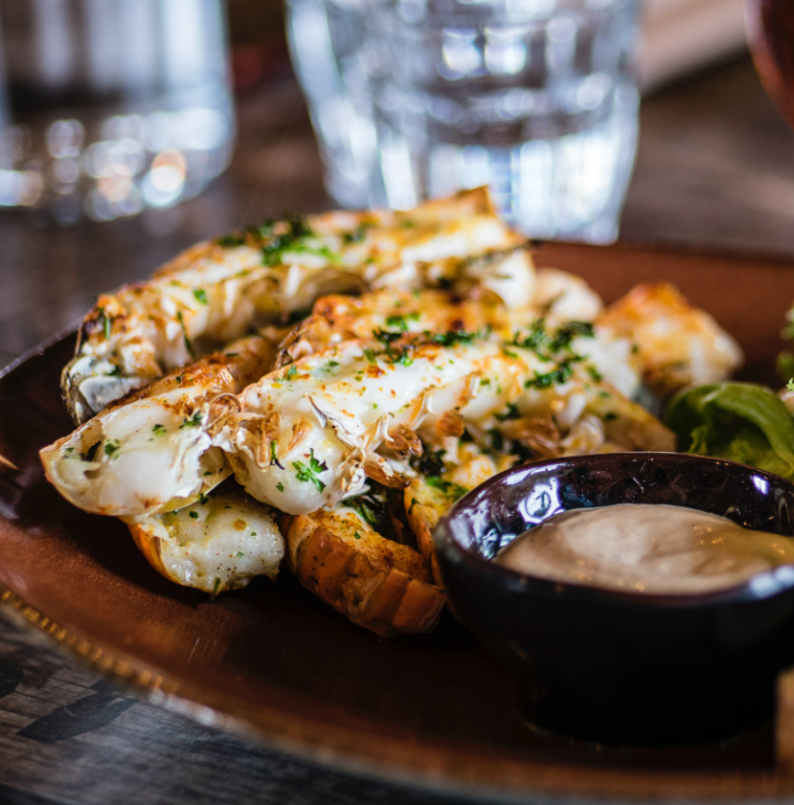 A plate of beautifully-spiced seafood with greens and 
                a dipping sauce